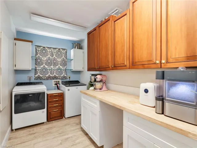 Utility room with a light wood-finish countertop, wood-finish upper cabinetry, and white base cabinetry