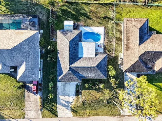 Property featuring a private swimming pool with surrounding patio, a concrete driveway, and a shingled roof