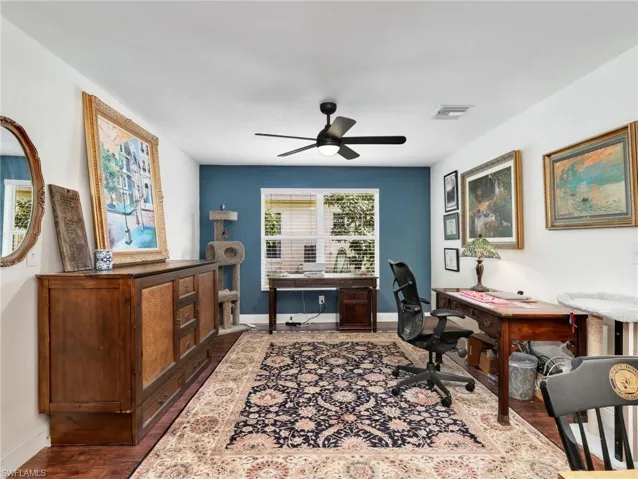 Dedicated room featuring wood-finish flooring, a ceiling fan with integrated lighting, and a window with blinds