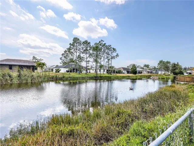 Waterfront property featuring a serene pond, mature trees, and lush green landscaping