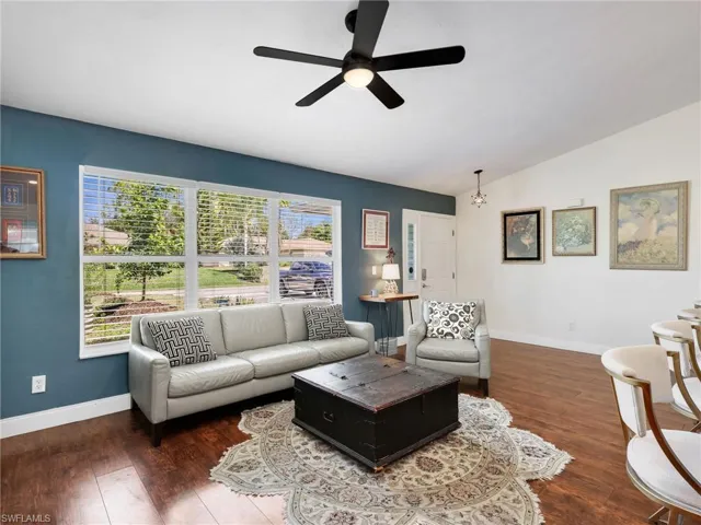 Spacious living area featuring large windows with blinds, wood-finish flooring, a contemporary ceiling fan, and white baseboards