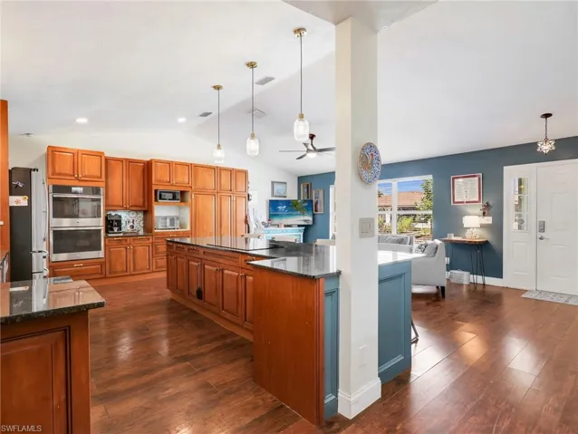 Kitchen featuring wood-finish flooring, extensive wood cabinetry, granite countertops, and stainless steel double ovens