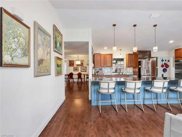 Kitchen island with seating for four, pendant lighting, and dark countertops