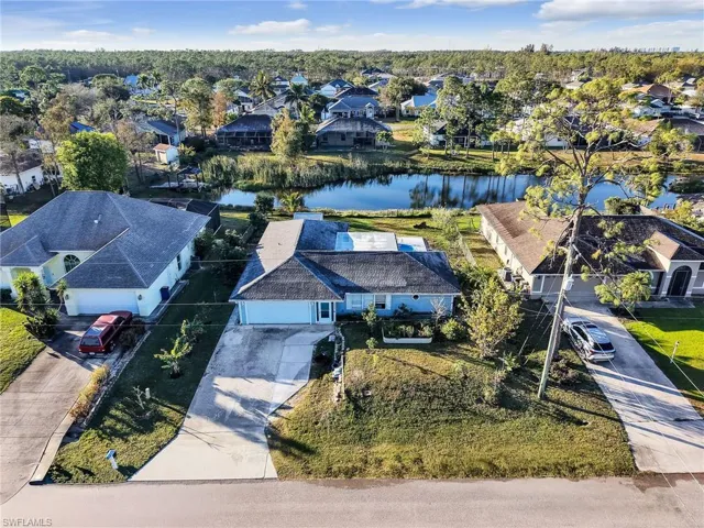 Waterfront property featuring a private boat dock, mature landscaping, and a paved driveway