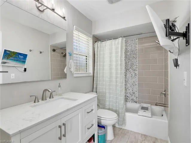 Bathroom featuring a white vanity with a light-toned countertop, a large wall mirror, and a shower/tub combination with subway tile and an accent mosaic
