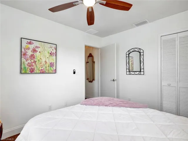 Room featuring a ceiling fan with wood-finish blades and a white ceiling