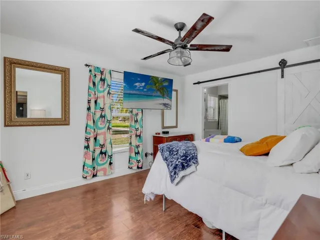Spacious room featuring wood-finish flooring, a contemporary ceiling fan, and a barn door entry to an additional space