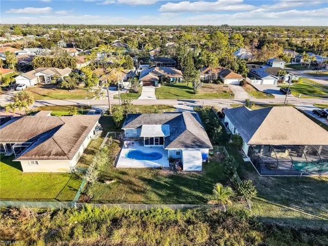 Residential property featuring a private swimming pool, screened lanai, manicured lawn, and mature palm trees