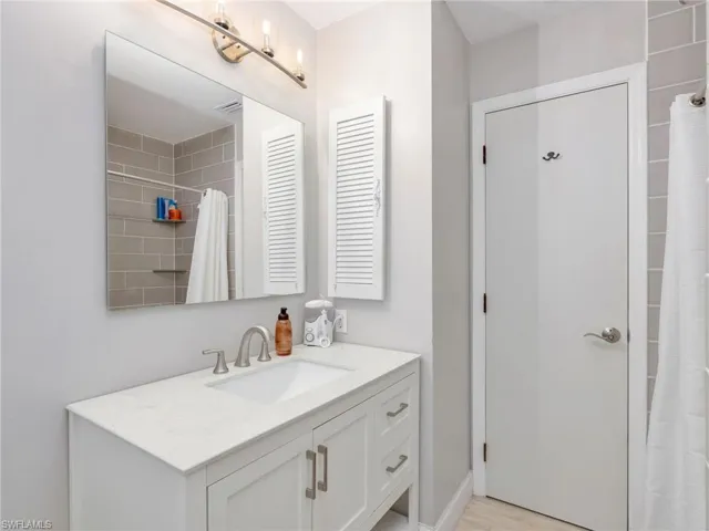 Bathroom vanity featuring a light countertop, under-mount sink, and brushed nickel faucet