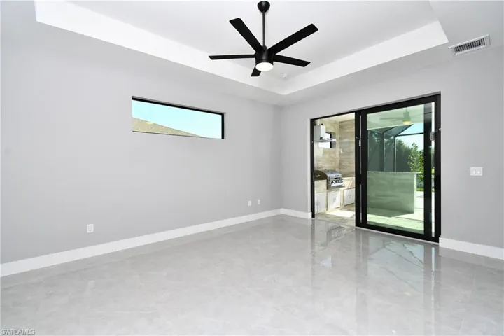 Empty room featuring tile patterned flooring, a raised ceiling, and a wealth of natural light