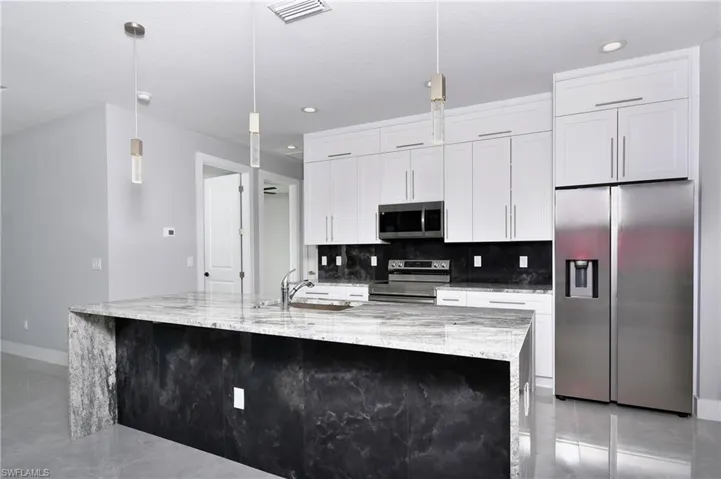 Kitchen with white cabinetry, a spacious island, backsplash, and stainless steel appliances
