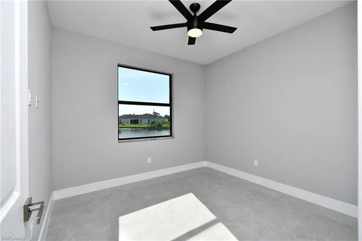 Tiled empty room featuring a water view and ceiling fan