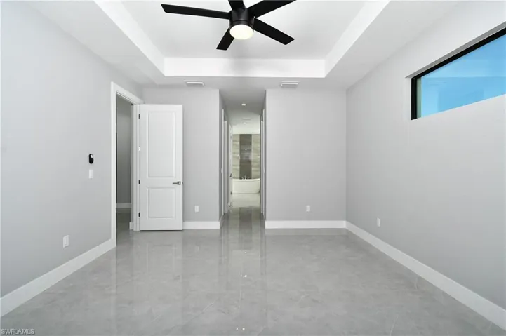 Tiled spare room featuring ceiling fan and a tray ceiling