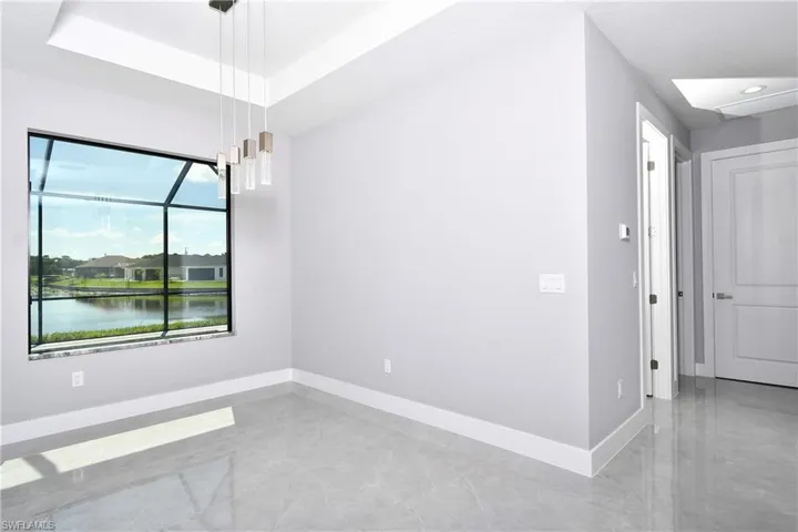 Unfurnished room with tile patterned floors, a water view, and a tray ceiling