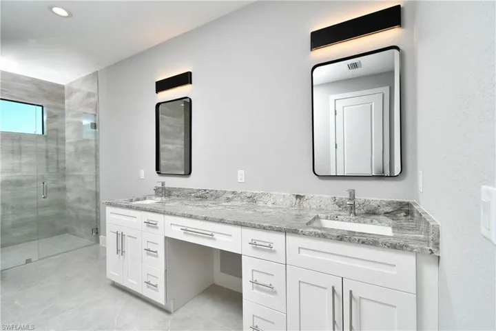 Bathroom with walk in shower, tile patterned floors, and double sink vanity