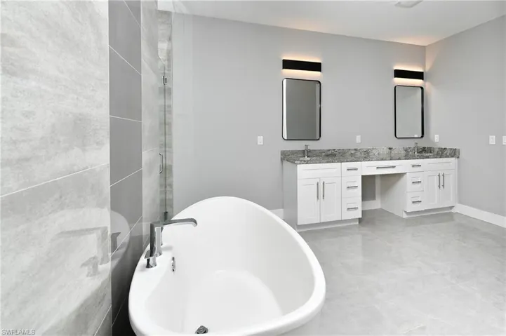 Bathroom with double vanity, tile patterned floors, and a bathing tub