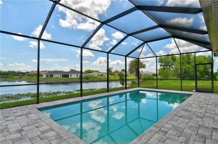 View of pool featuring glass enclosure and a patio area