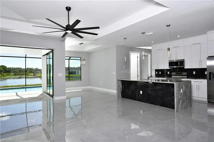 Kitchen featuring light tile patterned flooring, ceiling fan, a tray ceiling, hanging light fixtures, and appliances with stainless steel finishes