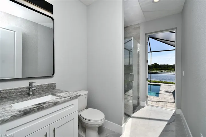 Bathroom with vanity, tile patterned floors, a shower with shower door, a water view, and toilet