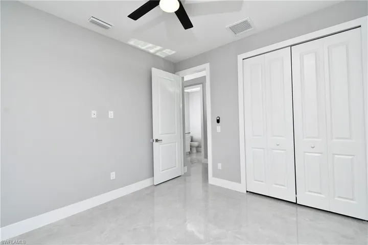Unfurnished bedroom featuring a closet, light tile patterned floors, and ceiling fan