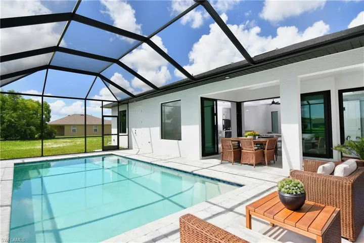 View of swimming pool featuring a patio, ceiling fan, glass enclosure, and an outdoor hangout area