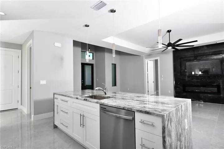 Kitchen featuring white cabinets, dishwasher, ceiling fan, light stone countertops, and sink