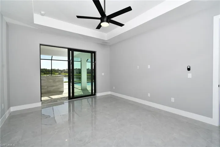 Unfurnished room with light tile patterned flooring, ceiling fan, and a tray ceiling