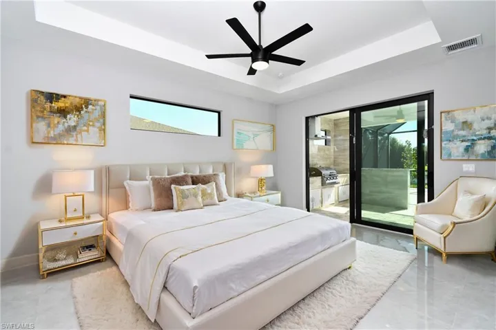 Bedroom featuring access to exterior, ceiling fan, light tile patterned flooring, and a tray ceiling