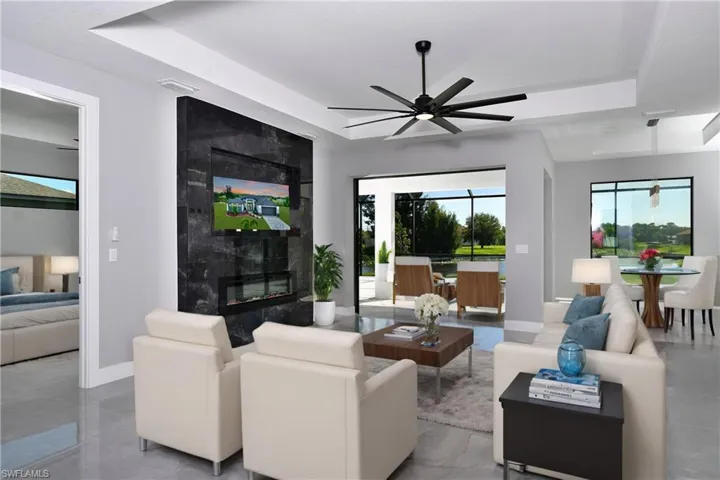 Living room featuring ceiling fan, a tray ceiling, light tile patterned floors, and a premium fireplace