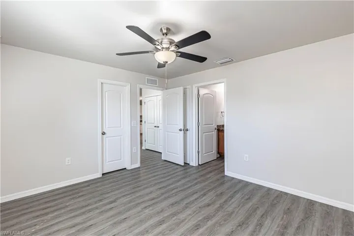 Unfurnished bedroom featuring wood finished floors, ceiling fan, and ensuite bath
