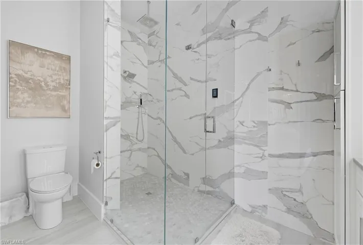 Bathroom featuring a marble finish shower and toilet