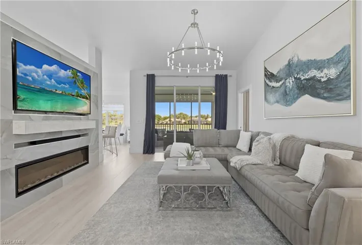 Living area with a glass covered fireplace, wood finished floors, and a chandelier