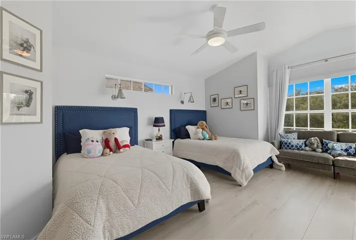 Bedroom featuring multiple windows, vaulted ceiling, a ceiling fan, and wood finished floors