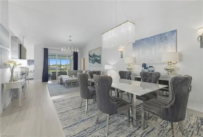 Dining space featuring a chandelier, light wood-type flooring, and lofted ceiling