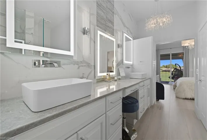 Full bathroom featuring double vanity, connected bathroom, light wood-style flooring, and a chandelier