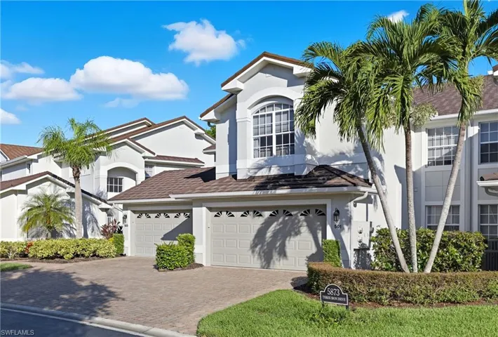 View of front facade with stucco siding, decorative driveway, and a garage