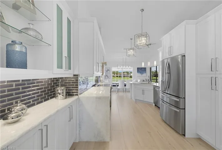 Kitchen featuring white cabinetry, open shelves, hanging light fixtures, stainless steel appliances, and light stone countertops