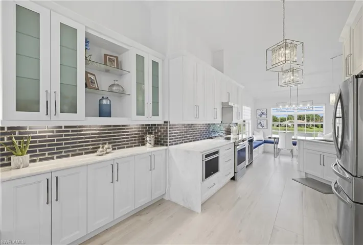 Kitchen with open shelves, white cabinetry, decorative light fixtures, appliances with stainless steel finishes, and backsplash