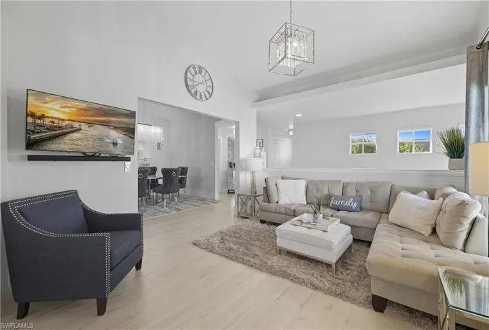Living room with a chandelier, wood finished floors, and high vaulted ceiling