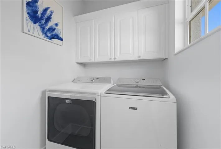 Washroom with washer and clothes dryer and cabinet space
