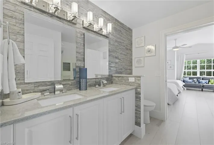 Bathroom with double vanity, decorative backsplash, connected bathroom, and a ceiling fan