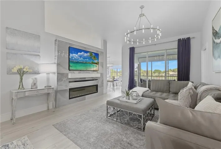 Living room featuring light wood finished floors, a glass covered fireplace, and a chandelier