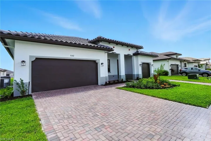 Mediterranean / spanish-style home featuring decorative driveway, a garage, a front lawn, and stucco siding