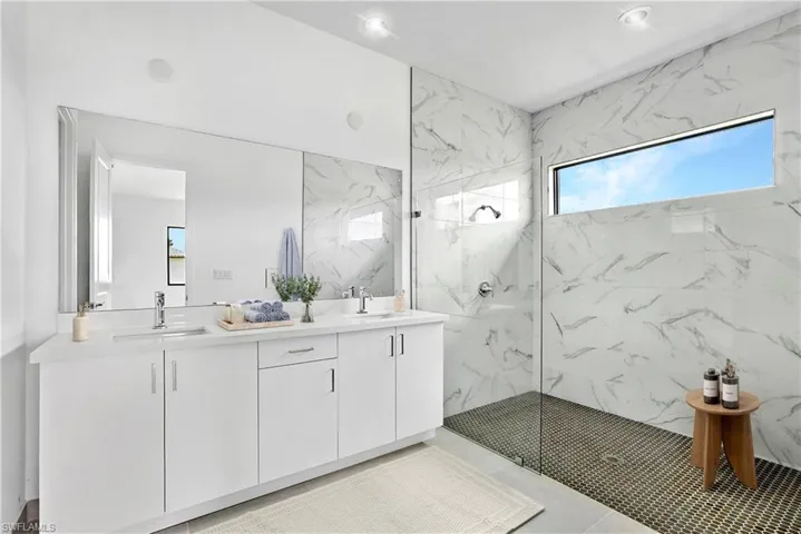 Master Bathroom with a marble finish shower, double vanity, and light tile patterned flooring