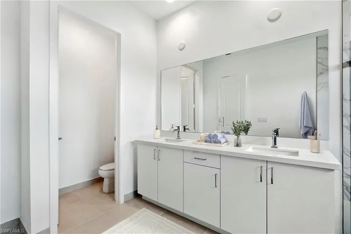 Master Bathroom with double vanity and light tile patterned flooring