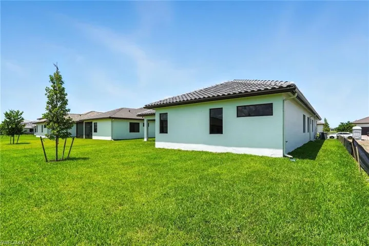 Rear view of property featuring a lawn and stucco siding