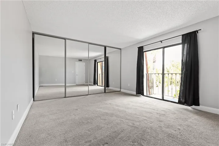 Unfurnished bedroom with carpet, a closet, a textured ceiling, and access to outside