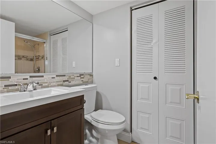 Bathroom with a closet, vanity, backsplash, and a tile shower