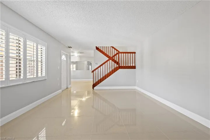 Hall featuring light tile patterned floors, a textured ceiling, and stairs