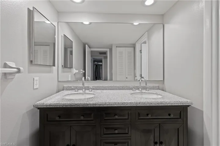 Bathroom with a closet, double vanity, and a textured wall